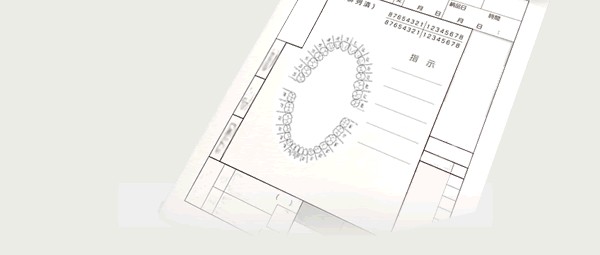 歯科技工指示書の実物写真。歯列（上顎・下顎の歯並び）を示すイラスト図と、氏名・依頼日・完成日等の記入欄、歯科医院控え・技工所控えの2枚複写であることを示す同一の通し番号が2段印字されている